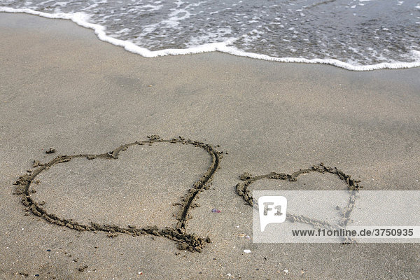Two hearts carved into the sand on a beach