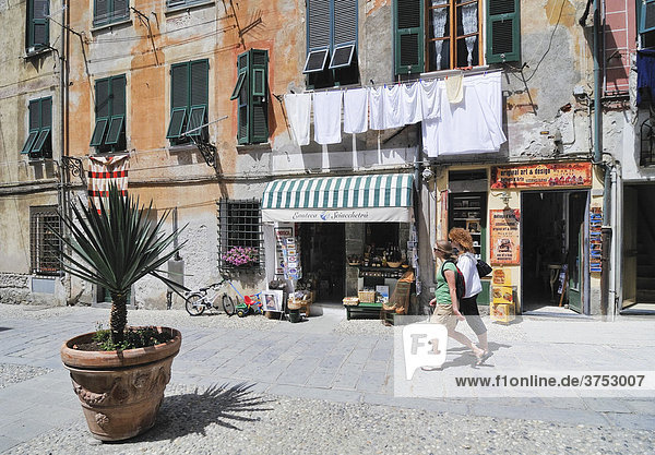 Straßenszene  zwei junge Frauen gehen entlang einer Häuserfassade mit kleinem Geschäft und Wäsche an der Wäscheleine  Vernazzo  Ligurien  Cinque Terre  Italien  Europa