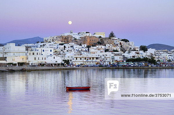 Weiße Häuser  Vollmond im rosa Abendhimmel über Naxos Stadt mit Kastro  venezianische Festung  rotes Holzboot im Meer  Kykladen  Griechenland  Europa