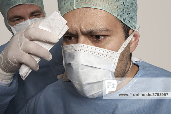 Chirurg wird während der Operation vom Schweiß befreit
