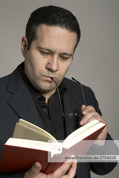 Geschäftsmann mit Brille liest stehend ein Buch