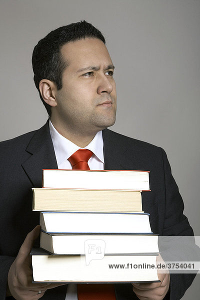 Geschäftsmann mit entspanntem Gesicht schleppt einen Bücherstapel
