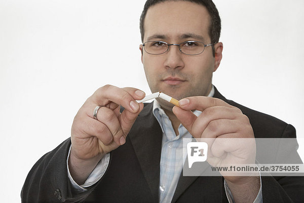 Mann zerbricht Zigarette zur Raucherentwöhnung