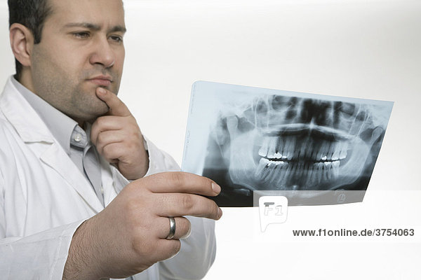 Zahnarzt begutachtet Röntgenaufnahme eines Kiefers