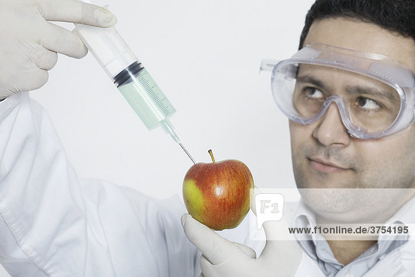 Chemiker spritzt Substanz in Apfel