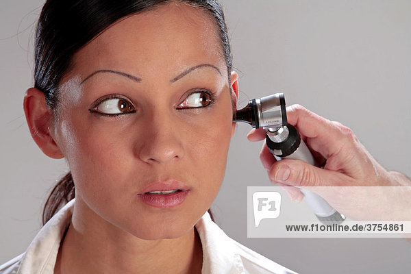 Ohrenuntersuchung mit Otoskop beim Hals-Nasen-Ohren-Arzt an einer jungen Frau