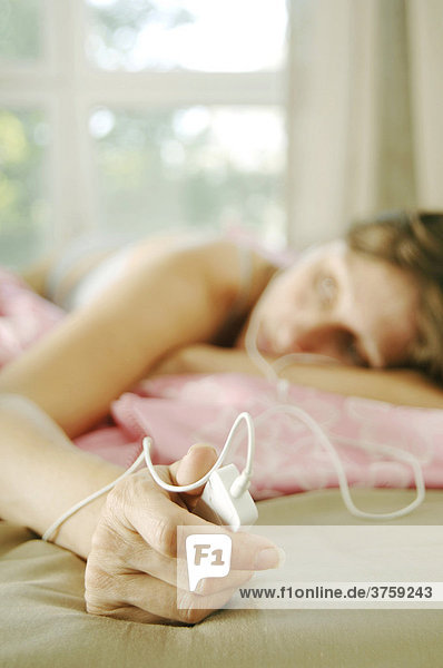 Frau beim Musikhören im Bett