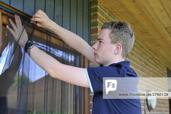 Jugendlicher bringt Insektenschutzvorhang an Balkontür