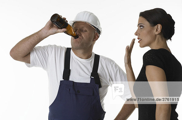 Frau versucht einen Handwerker beim Biertrinken zu stoppen
