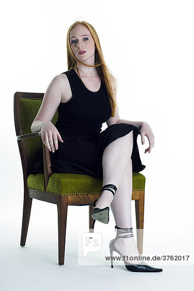 Redheaded young woman sitting on an armchair