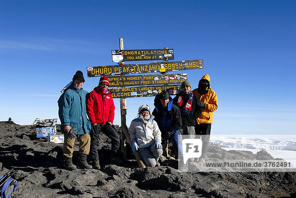 Successful group of mountaineers at the sign on the summit Uhuru Peak (5895 m) crater rim Kilimanjaro Tanzania