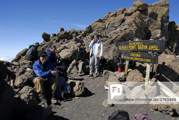Erfolgreiche Gruppe Bergsteiger am Schild auf dem Gipfel Gilman's Point (5681 m) Kraterrand Kilimandscharo Tansania