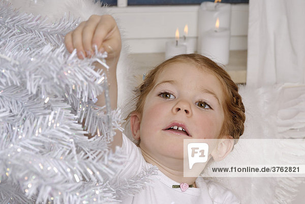 Kind schmückt einen weissen Weihnachtsbaum