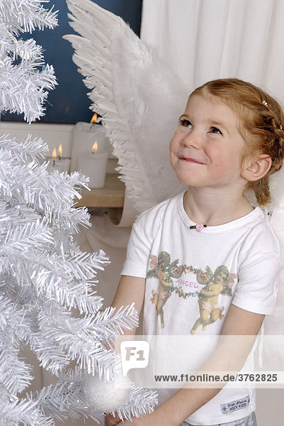 Kind schmückt einen weissen Weihnachtsbaum
