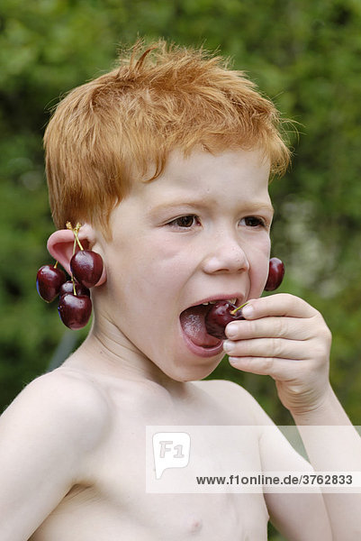Junge beim Kirschen essen mit Ohranhänger