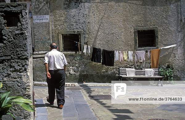 Alter Mann am Gehweg und aufgehängte Wäsche in Roggiano Gravina  Sila Grande  Kalabrien  Italien