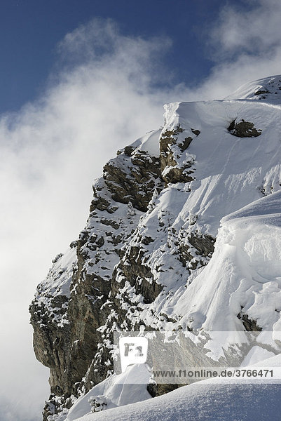 Ice fog circulates rocky peak loaded with heavy snow drifts Tyrol Austria