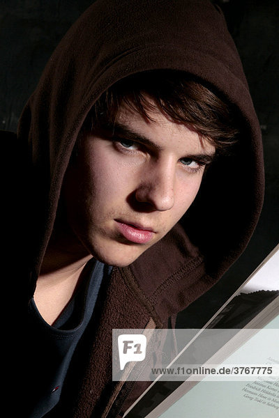 Young man wearing hooded sweatshirt (hoodie) holding a book