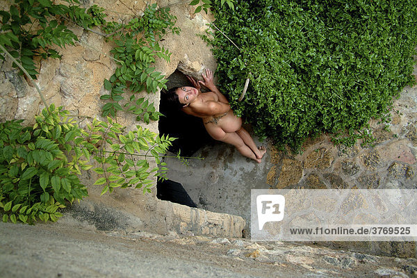 View from above  naked young woman standing in the archway of a rock garden  Mallorca  Balearic Islands  Spain  Europe