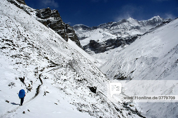 Trekker mit Rucksack in verschneiter Berglandschaft auf dem Weg nach Thorung Phedi Annapurna Region Nepal