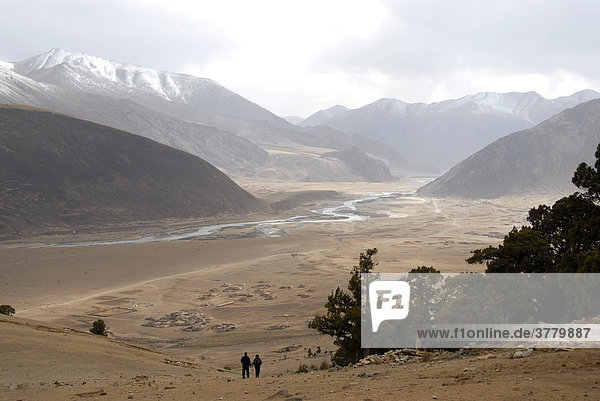 Wide river valley forest and snow covered mountains at Reting monastery Tibet China