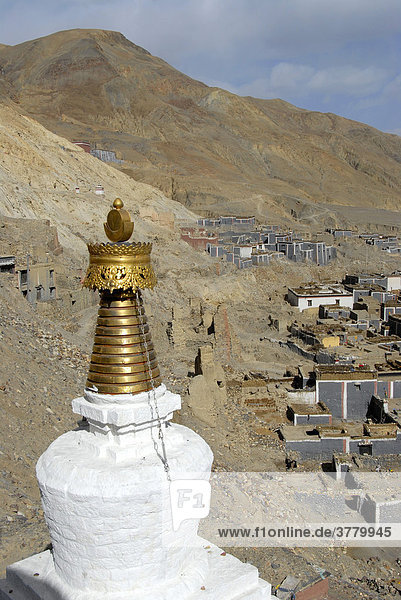 Tibetischer Buddhismus Stupa mit goldener Spitze traditionelle Häuser mit grau und dunkelrot gestrichener Mauer an Berghang Kloster Sakya Tibet China
