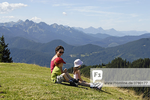 Familiy resting from hiking wandering mountain hiking on the Hinteres Hoernle near Bad Kohlgrub Upper Bavaria Alps Germany