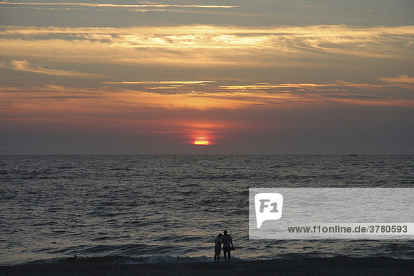 A couple watches sunset on the beach of Sylt  Schleswig-Holstein  Germany