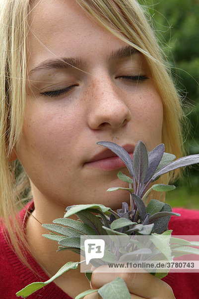 Junge Frau riecht an einem Strauss Salbei Salvia