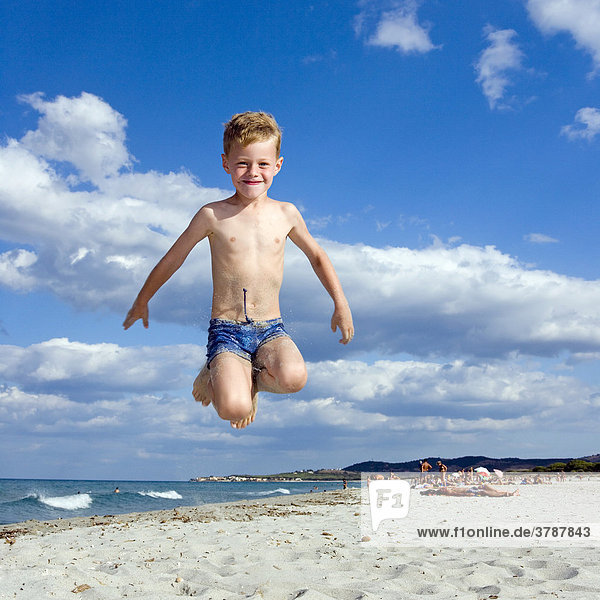 A boy five years old does a caper on the beach of La Caletta Sardinia Italy