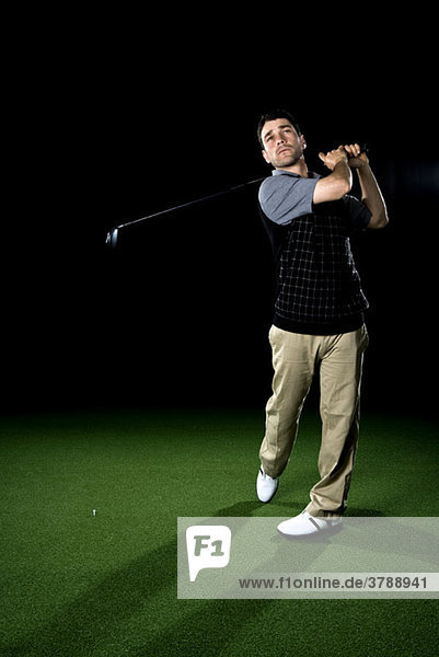 Ein Golfer schwingt einen Schläger  Porträt  Studioaufnahme