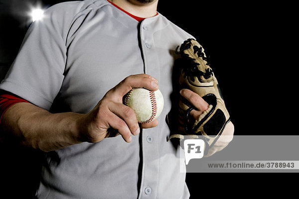 A baseball player holding a baseball  midsection view