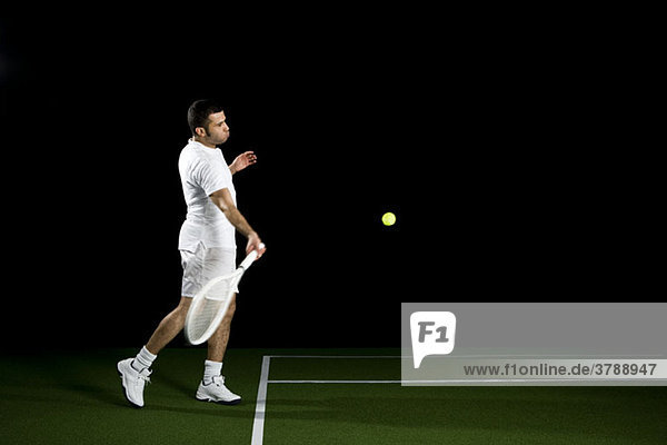 Ein Tennisspieler im Begriff  einen Ball zu schlagen  Studioaufnahme  Porträt