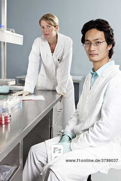 Two lab technicians in a laboratory  looking at camera