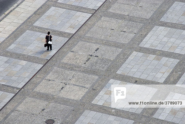 Eine Frau  die allein auf einem städtischen Platz steht.