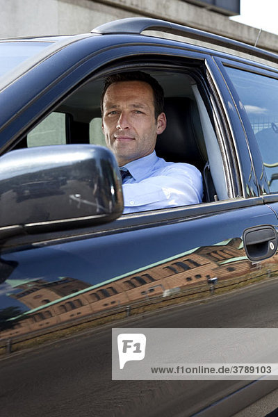 A businessman in his car  looking at camera