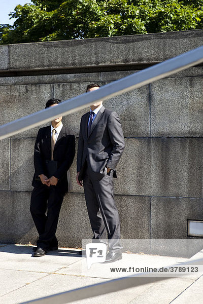 Zwei Geschäftsmänner  Gesichter verdeckt durch das Geländer