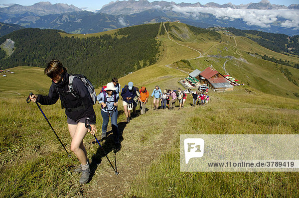 Big hiking group climbs up a grassy slope Haute-Savoie France