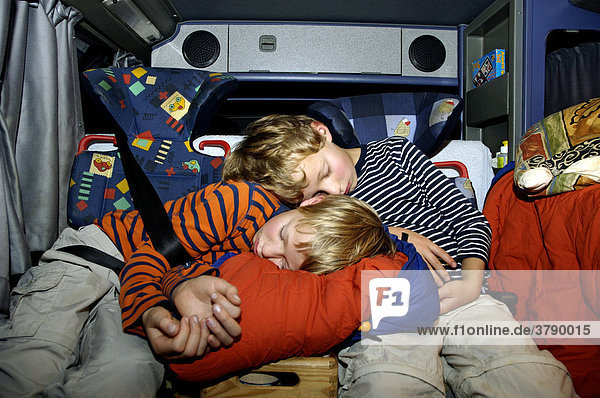 Exhausted children 8 and 10 years old sleeping in the car in the security seats