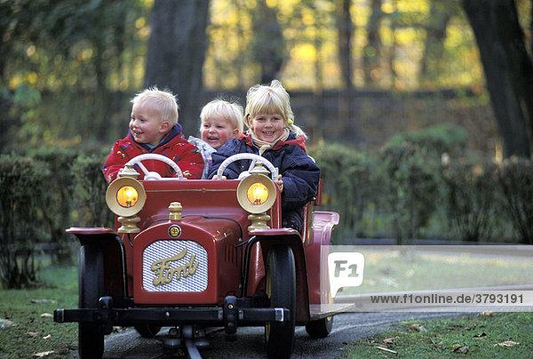 Three children driving in a toy car
