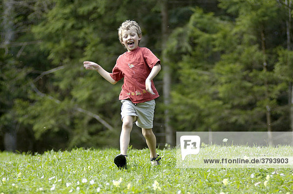 One seven-ywear-old boy running down a meadow in spring