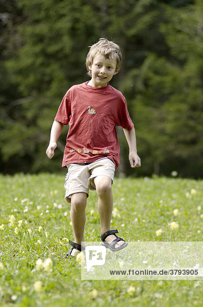 One seven-ywear-old boy running down a meadow in spring