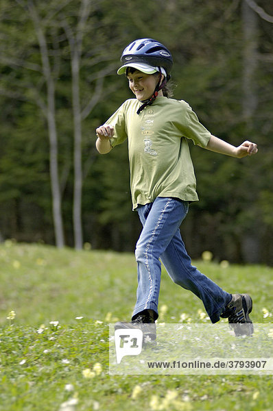 One eight-year-old girl running down a meadow in spring