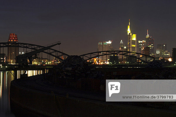 Großartige Skyline von Frankfurt am Main mit den Wolkenkratzern der Banken bei Nacht mit einer Eisenbahnbrücke im Vordergrund
