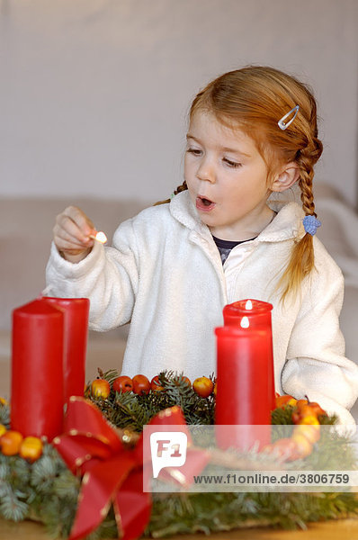 Kind mit Adventskranz und Kerzen