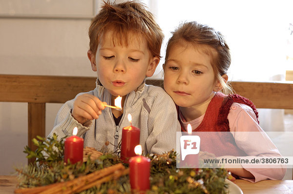 Kinder in der Vorweihnachtszeit im Advent mit Kerzen und Adventskranz