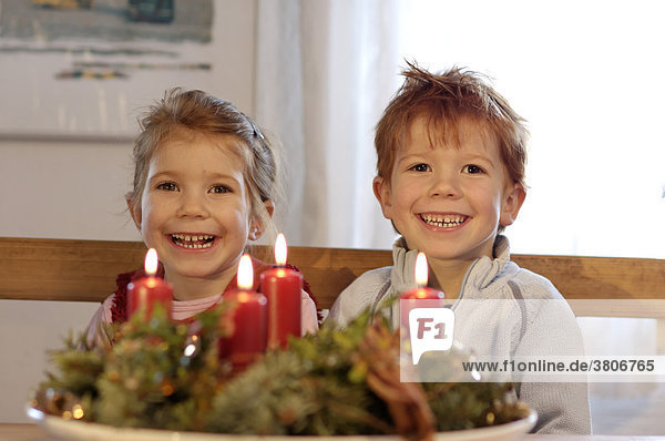 Kinder in der Vorweihnachtszeit im Advent mit Kerzen und Adventskranz