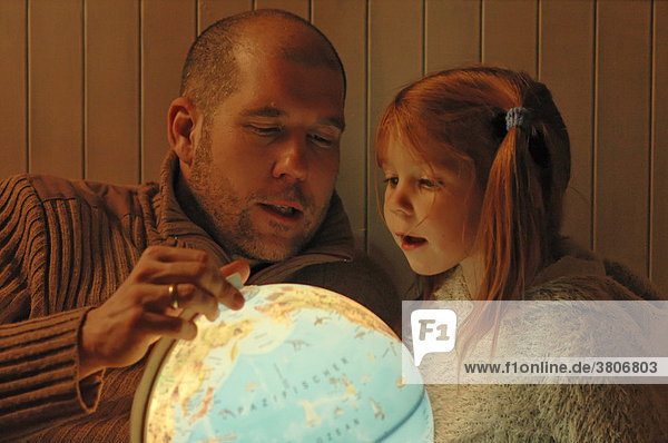 Vater studiert einen Globus mit seinem Kind