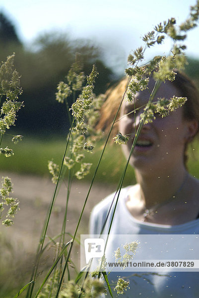 Junge Frau mit Heuschnupfen reagiert allergisch auf Gräser und Pollen Knäuelgras Dactylis