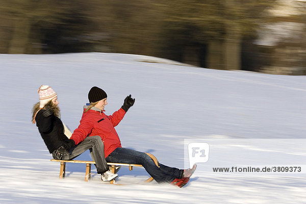 Two young women are sledging and have fun
